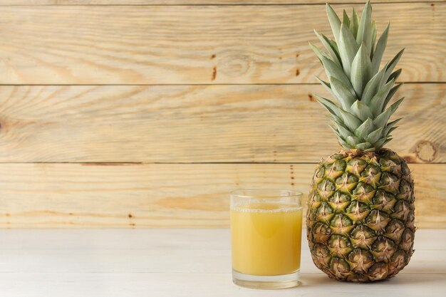 Ripe pineapple fruit and pineapple juice on a natural wooden table. summer.