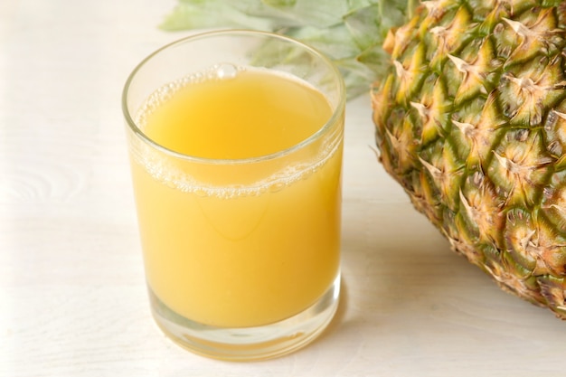 Photo ripe pineapple fruit and pineapple juice on a white wooden table. summer. close-up