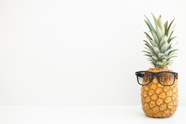 Ripe pineapple in sunglasses on a white background Summer vacation Hello summer