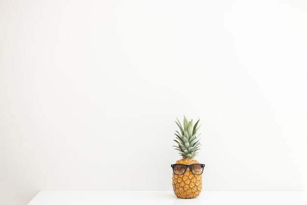 Ripe pineapple in sunglasses on a white background Summer vacation Hello summer