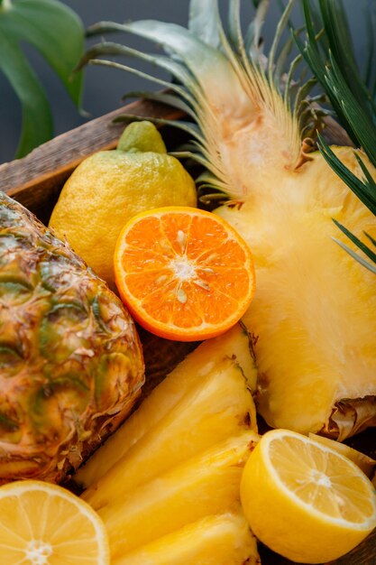 Ripe pineapple. Tropical fruits Mix wooden box. Tangerines oranges pineapples lemons. Sliced tropical citrus vitamin dessert as summer background. High quality stock photo