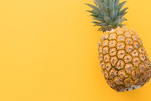 Ripe pineapple on a yellow background