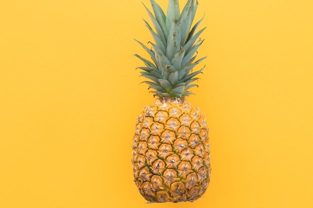 Ripe pineapple on a yellow background