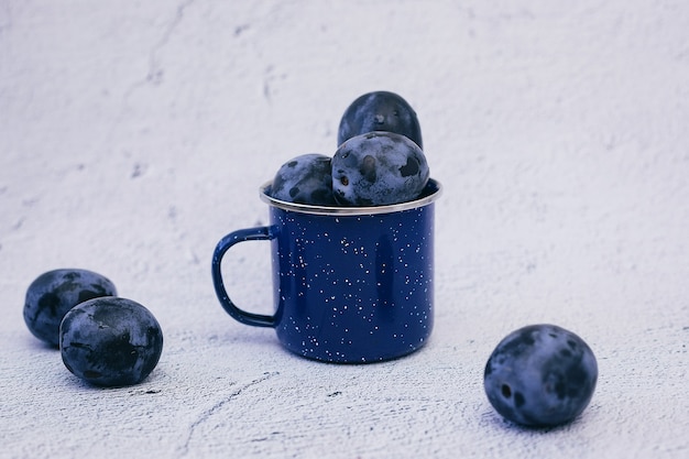 Photo ripe plums in a blue glass