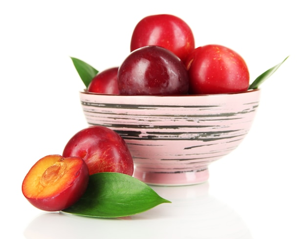 Ripe plums in bowl isolated on white