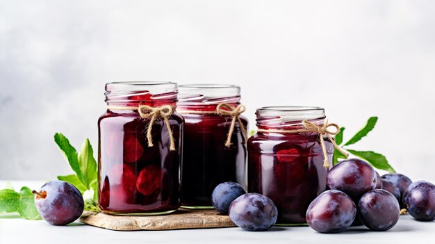 Ripe plums and plum compote in glass jars on the table Home canned food and harvest