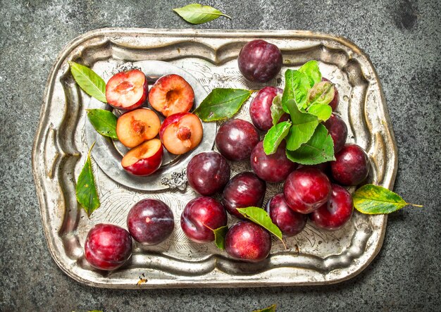 Ripe plums on a steel tray.