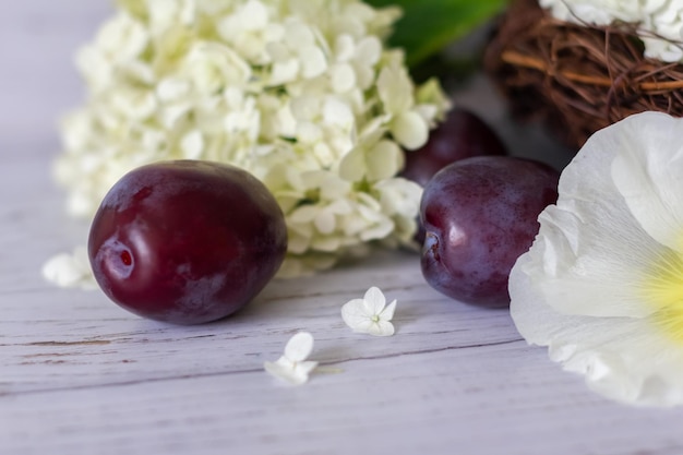 Ripe plums in a vine basket on a wooden background