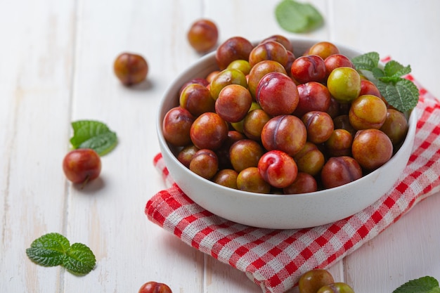 Ripe plums on the white wooden surface.