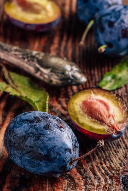 Ripe plums with leaves water drops and knife