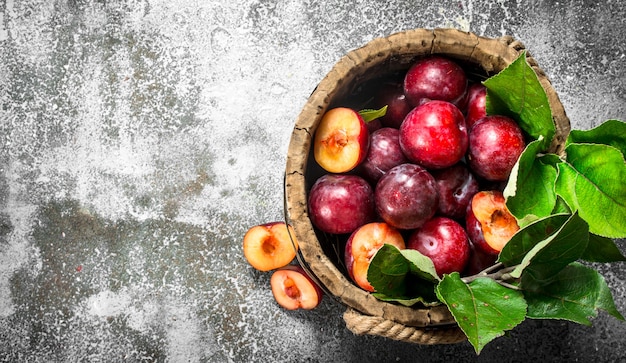 Ripe plums in a wooden bucket. On a rustic background.