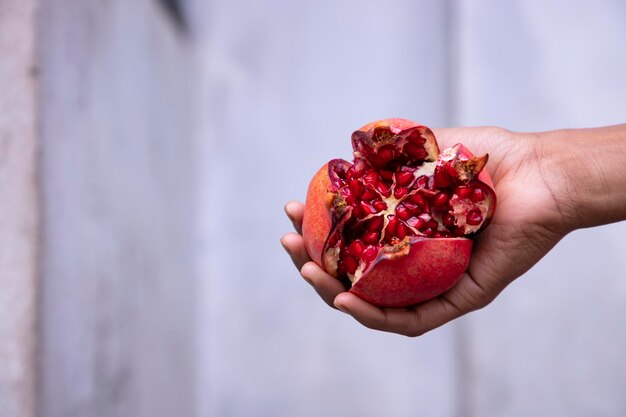 Ripe pomegranate fruit in hand on white background