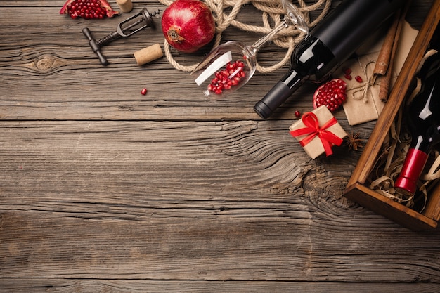 Foto frutta matura del melograno con un bicchiere di vino, una bottiglia e un regalo su un fondo di legno