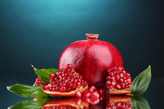 ripe pomegranate fruit with leaves on blue background