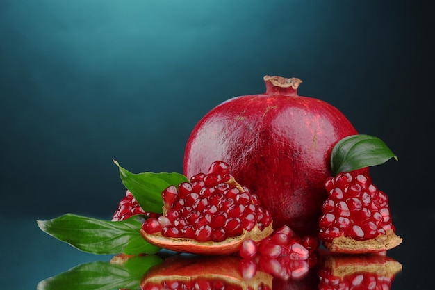 Ripe pomegranate fruit with leaves on blue background