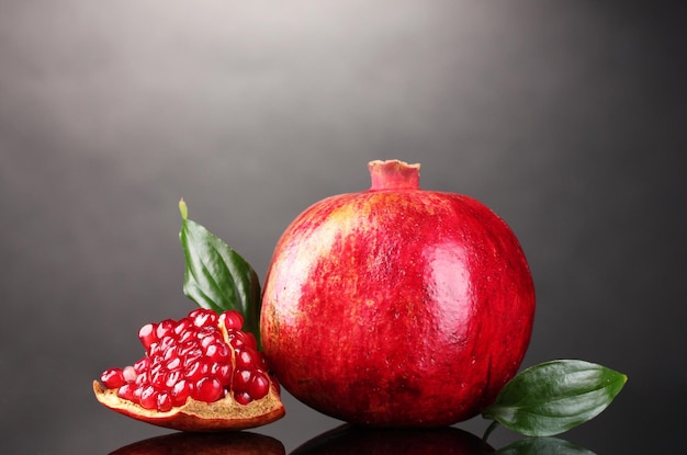 Photo ripe pomegranate fruit with leaves on gray background