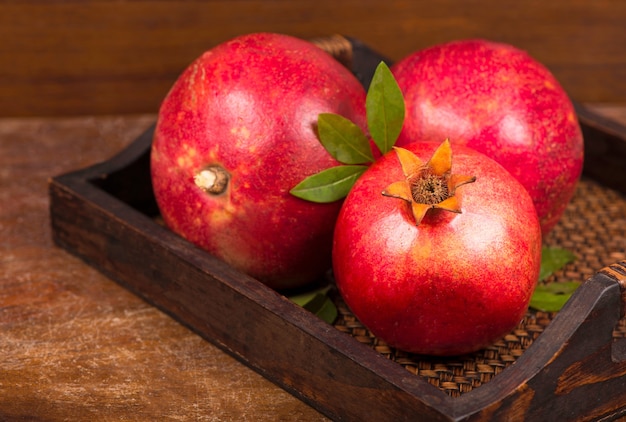 Ripe pomegranate fruits on the wooden background. Top view.