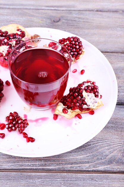 Ripe pomegranate and glass of juice on wooden table