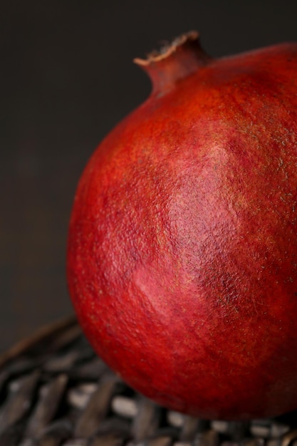 Ripe pomegranate on wicker mat on wooden background