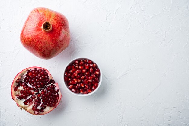 Ripe pomegranate with fresh juicy seeds, on white textured background