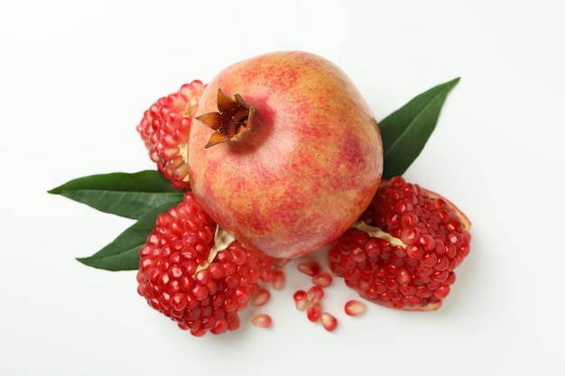 Ripe pomegranate with leaves on white background