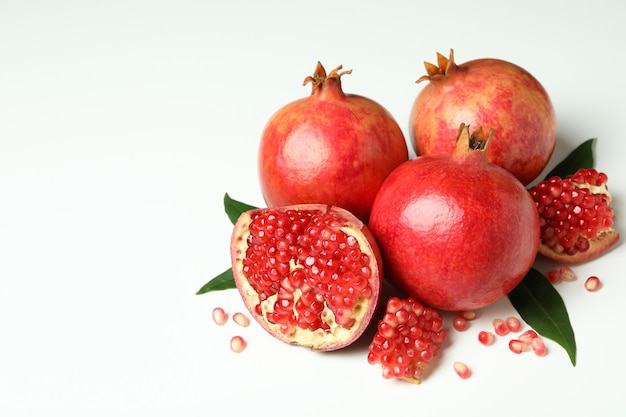 Ripe pomegranate with leaves on white background