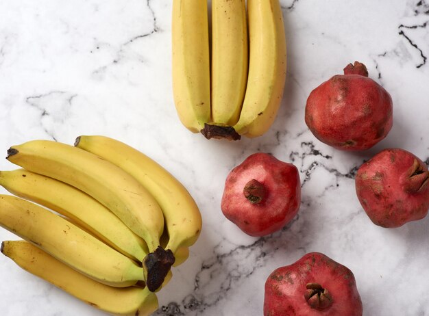 Ripe pomegranates and bananas on marble table