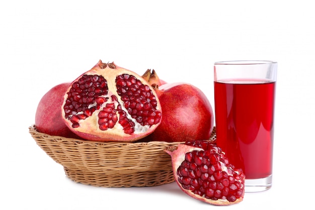 Ripe pomegranates on basket and glass of juice isolated on white background