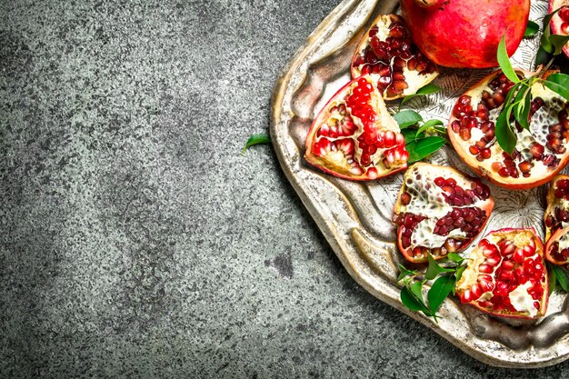 Ripe pomegranates on a steel tray. On a rustic background.