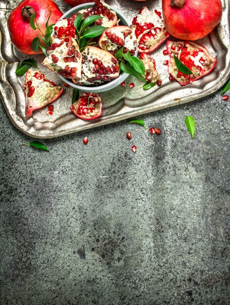 Ripe pomegranates on a steel tray. On a rustic background.