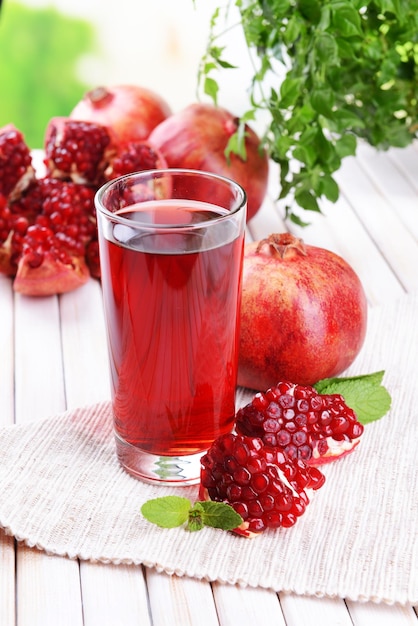 Ripe pomegranates with juice on table on light background