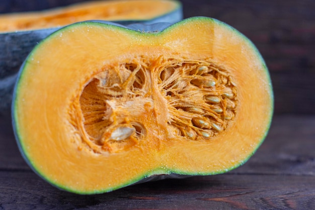 A ripe pumpkin with bright orange flesh cut in half on an old wooden table