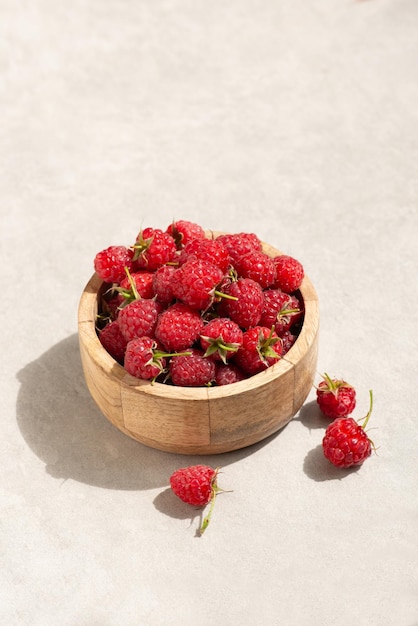 Ripe raspberry berries on a gray background in a wooden plate