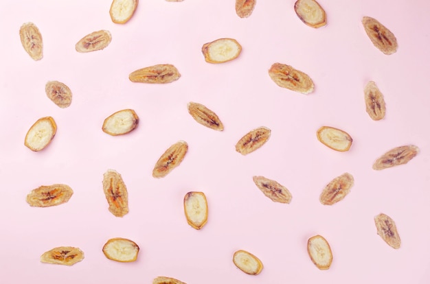 Ripe raw banana and dried banana slices chips scattered on white background. Fruit chips. Healthy eating concept, snack, no sugar. Top view, copy space.