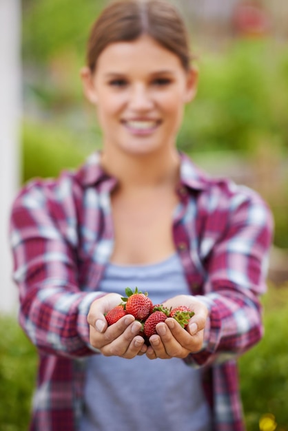 Ripe e pronto ritagliata colpo di una giovane donna felice in possesso di una manciata di fragole fresche