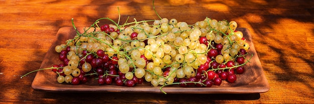 Фото Спелая красная и белая смородина на подносе на деревянном фоне куча ягод витаминов урожая
