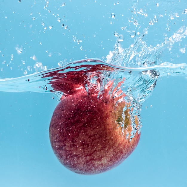 사진 잘 익은 빨간 사과가 맑은 물에 떨어지면서 많은 물보라를 형성합니다.