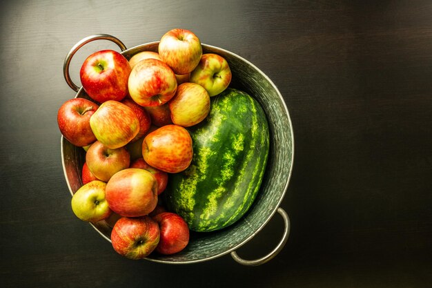 Ripe red apples and watermelon in washtub on dark background top view