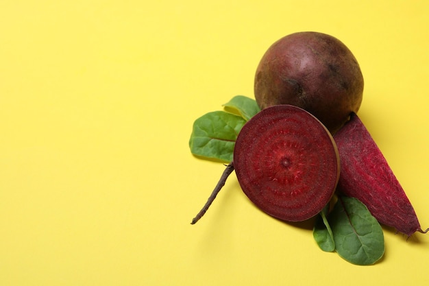 Ripe red beet with leaves on yellow background