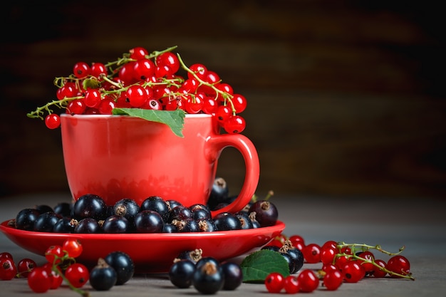 Ripe red and black currants on a wooden table.