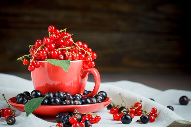 Ripe red and black currants on a wooden table.