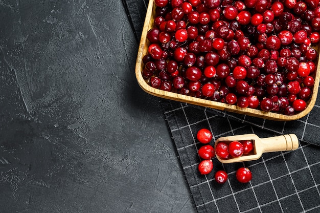 Photo ripe red cranberries in a wooden bowl  black surface    surface