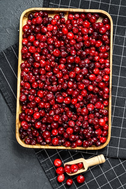 Ripe red cranberries in a wooden bowl  Black surface  