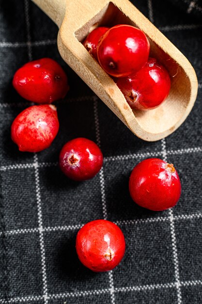 Ripe red cranberries in a wooden spoon. Close up. Black background. Top view