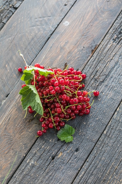 Ripe red currant berries in a bowl  on a rustic wooden background