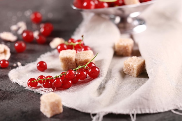 Ripe red currants with lamp sugar on table with sackcloth closeup