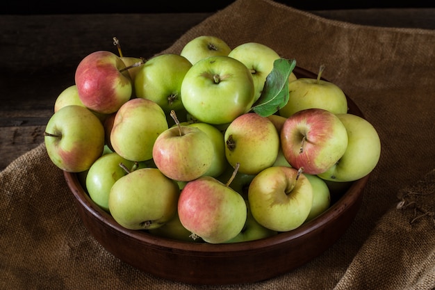 Ripe red and green apples on wooden background. Apples in bowl. Garden fruits Autumn fruit