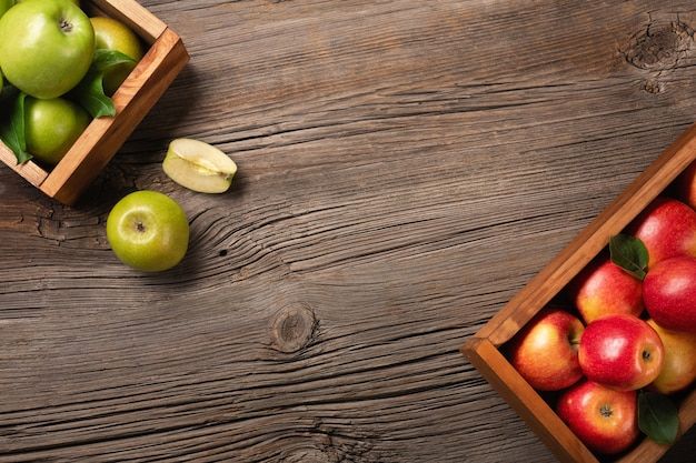 Ripe red and green apples in wooden box on a wooden table. 