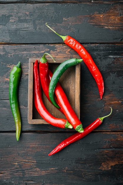 Ripe Red and green chili pepper set, in wooden box, on dark wooden background, top view flat lay