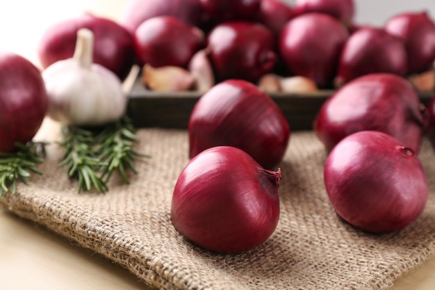 Ripe red onions, garlic and rosemary on table